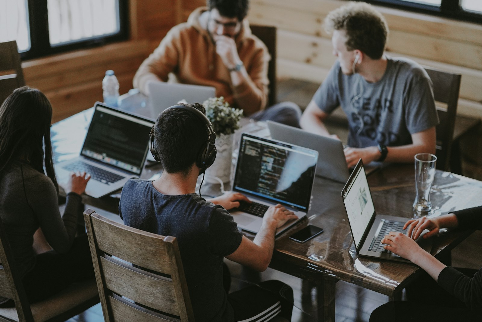 Equipo trabajando alrededor de una mesa con varios portátiles abiertos